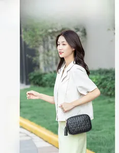 Detail of black quilted shoulder bag with golden chain strap and long leather tassel