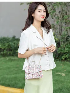 Detail of colorful tweed chain small square bag with elegant gold metal strap handle