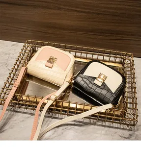 Detail of crocodile embossed crossbody bag with golden metal buckle and adjustable strap