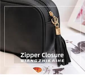 Detail of black PU leather bag with gold zipper closure and stylish tassel pendant
