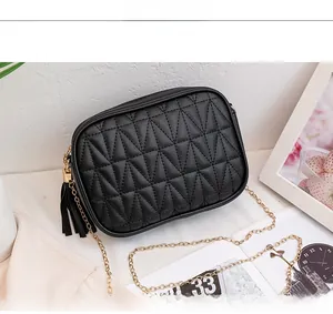 Detail of black quilted leather bag with gold chain strap and stylish tassel charm