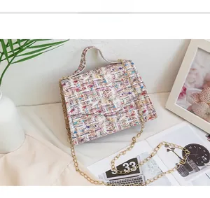 Detail shot of a tweed texture flap bag with a gold chain strap in a stylish setting