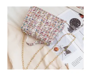 Close-up of small tweed chain bag with colorful woven texture on stylish trench coat
