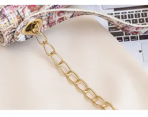 Close-up of golden chain and colorful tweed fabric on a printed small square bag