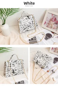 Detail view of a white PU crossbody bag with black graffiti art and gold chain strap