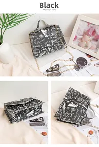 Detail of black faux leather bag with white graffiti prints and gold chain strap
