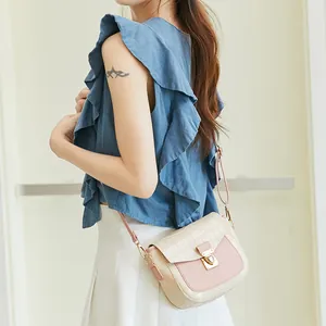 Pink and white crocodile pattern crossbody bag with golden lock on a female model