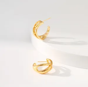 Moderne, mehrlagige, hohle C-förmige Goldohrringe auf einem weißen, minimalistischen Stein