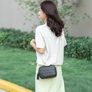 Quilted black crossbody bag with gold chain strap and tassel detail shown on model