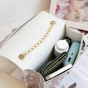 Vintage newspaper print small square bag with gold chain and organized daily essentials