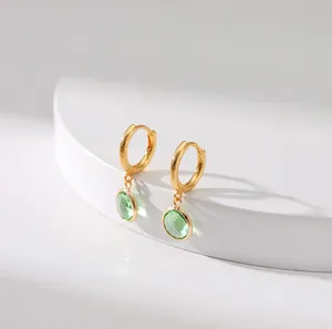 Detail of vintage gold earrings featuring two green zircon drops on a white stand