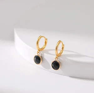 Detailed view of gold hoop earrings featuring elegant faceted round black gemstones