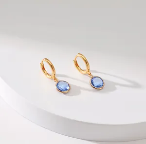 Detail of French vintage gold hoop earrings with faceted round blue crystal pendants