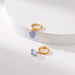 Close-up of vintage gold huggie earrings with a sparkling blue round zircon pendant