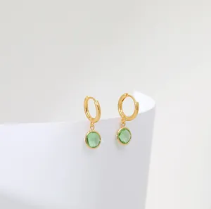Detailed macro shot of vintage gold hoop earrings with faceted green gemstone charms