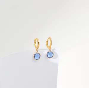 Detail of French vintage gold huggie earrings with sky blue faceted round zircon pendants