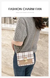 Detail view of plaid crossbody bag with gold lock and chain strap on female model