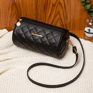 Elegant black cylinder crossbody bag with quilted pattern on a soft knit background