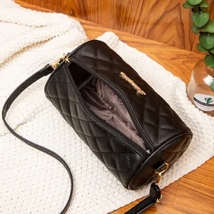 Quilted black cylinder crossbody bag with gold hardware on a cozy lifestyle background