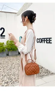 Détail d'un sac bandoulière marron en cuir PU matelassé avec logo doré à l'extérieur
