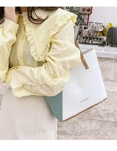 Close-up of mint green contrast tote bag with fashion leather stamp and gold rivet details