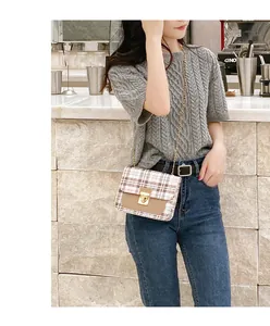 Close-up of a stylish checkered crossbody bag featuring gold chain and metallic buckle lock