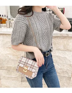 Close-up of small plaid crossbody bag with gold chain strap and metal lock closure
