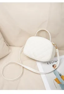 Détail d'un sac demi-lune blanc matelassé avec des ferrures dorées et une poignée