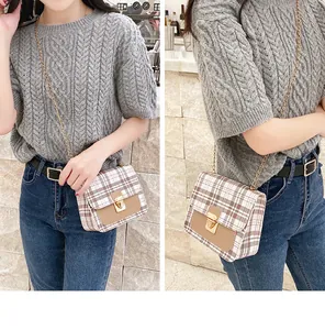 Detailed close-up of plaid crossbody bag featuring a golden buckle and chain strap