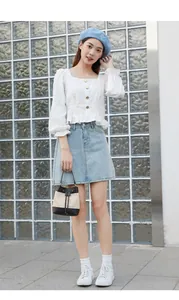 Détail de la blouse blanche à col carré avec boutons en bois et sac seau en maille