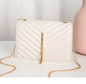 Detail of beige quilted chevron handbag with gold vertical bar and elegant tassel chain