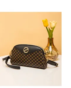 Gros plan détaillé du logo S doré sur le sac bandoulière noir avec motifs géométriques