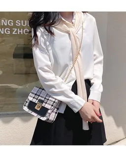 Detail of checkered crossbody bag with gold chain strap and lock shown on a model