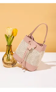Détail du sac seau bicolore avec texture en paille tressée et fermeture à cordon en rose