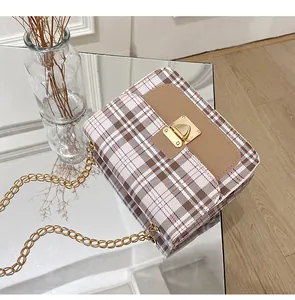 Detail of classic plaid crossbody bag with brown leather flap and gold chain strap