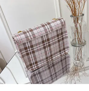 Detail view of plaid patterned fabric and golden metal rings on the crossbody bag