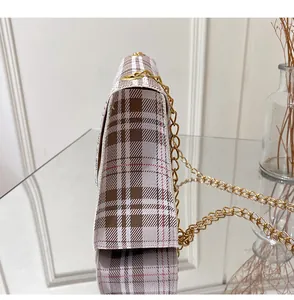 Detail of plaid patterned crossbody bag with gold chain strap and textured fabric finish