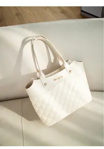 Détail du sac seau beige avec coutures matelassées et logo en métal doré brillant
