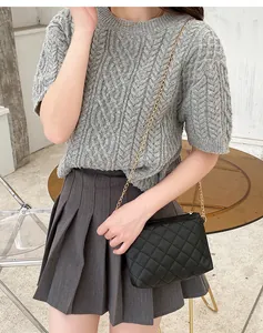 Borsa a tracolla nera trapuntata con catena dorata indossata su maglione grigio e gonna