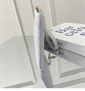 Κοντινό πλάνο λευκής τσάντας με σχέδιο κροκόδειλου, χρυσό φερμουάρ και προσεγμένες ραφές