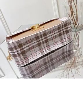 Detail of checkered crossbody bag with gold lock and chain strap on mirror