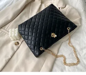 Detail der schwarzen Stepptasche mit Goldkette und Perle auf einem beigen Sakko