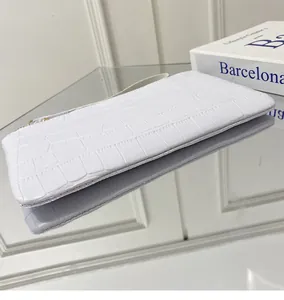 Λεπτομέρεια λευκής τσάντας clutch με κροκό σχέδιο, λουράκι καρπού και χρυσό φερμουάρ