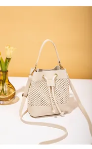 Détail du sac seau minimaliste en cuir PU crème et paille tissée avec cordon de serrage