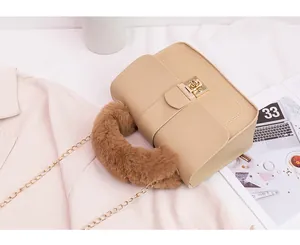 Detail of beige faux leather handbag featuring brown faux fur handle and gold metal chain