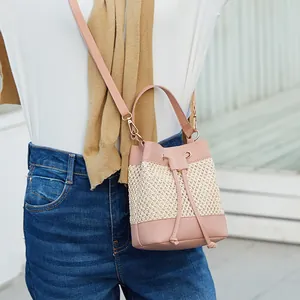 Sac seau en cuir rose et paille avec fermeture à cordon et bandoulière amovible