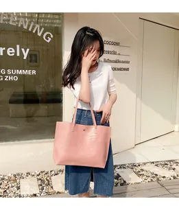 Detailed close-up of pink crocodile pattern tote bag with slim handles and metal buckle