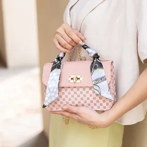 Sac bandoulière rose avec motif géométrique et foulard en soie sur la poignée