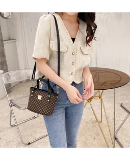 Brown mini bucket bag with monogram pattern and gold hardware held by a model