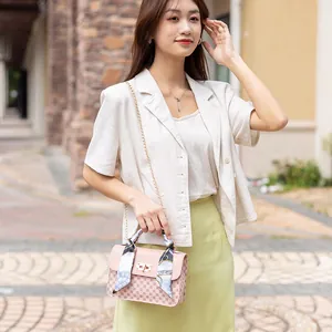 Sac bandoulière rose avec motif monogramme, chaîne dorée et détail de foulard en soie